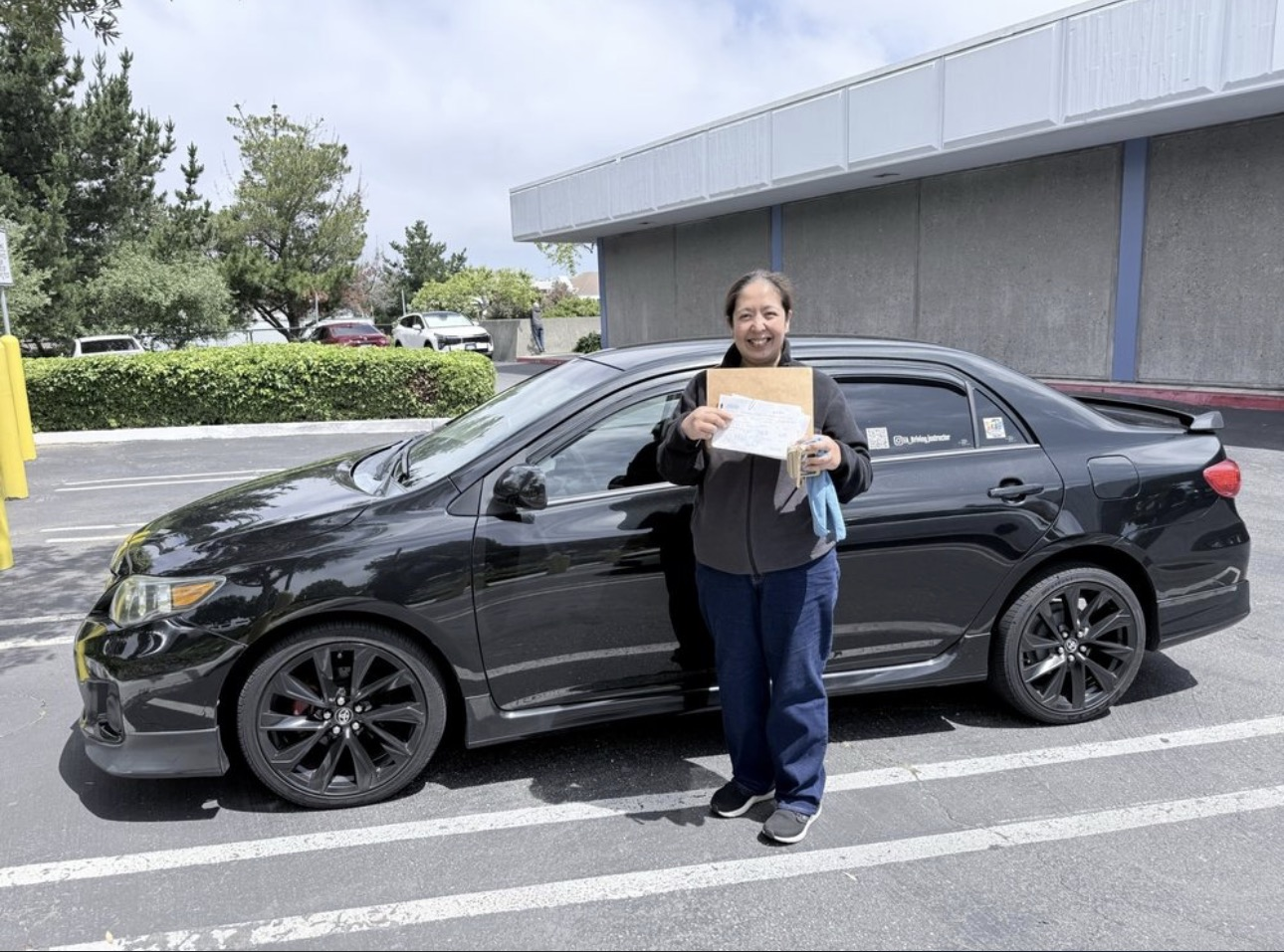 Smiling student holding her pass paperwork beside the training car